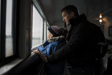 Vater und Tochter schauen durch das Fenster - CAVF56132