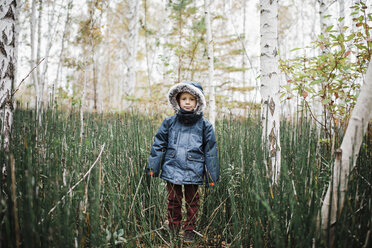 Porträt eines Jungen mit Kapuzenjacke, der inmitten eines Waldes steht - CAVF56133