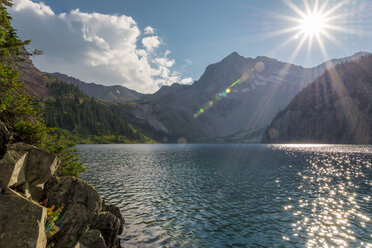 Scenic view of lake against mountains in forest during sunny day - CAVF56147