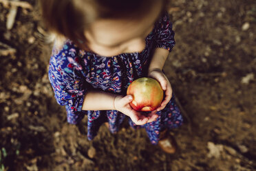 High-Winkel-Ansicht von Baby-Mädchen hält gegessen Apfel beim Gehen auf Feld - CAVF56163