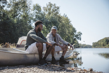 Männliche Freunde unterhalten sich auf einem Boot am Seeufer gegen den klaren Himmel - CAVF56273