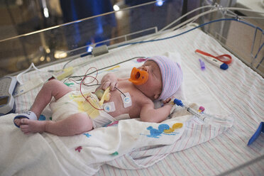 High angle view of newborn baby boy with medical equipment sleeping in crib at hospital - CAVF56306