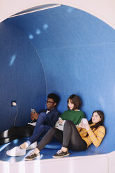 Freunde benutzen Smartphones, während sie in der Bibliothek sitzen - CAVF56321