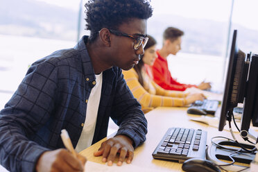 Studenten, die an einem Tisch in der Bibliothek sitzen und an Desktop-Computern lernen - CAVF56358