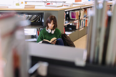 Hoher Blickwinkel einer Frau, die in einer Bibliothek sitzt und ein Buch liest - CAVF56362