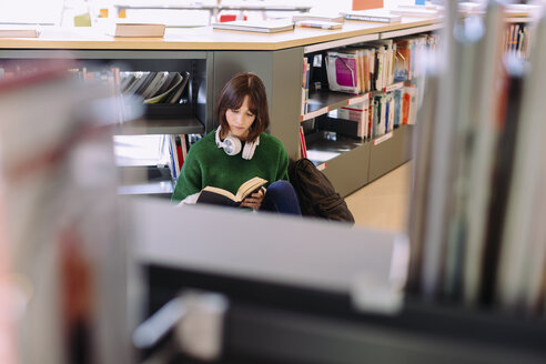 Hoher Blickwinkel einer Frau, die in einer Bibliothek sitzt und ein Buch liest - CAVF56362