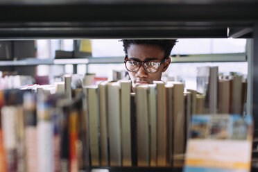 Mann sucht Bücher im Regal in der Bibliothek - CAVF56363