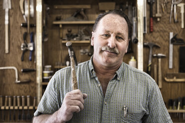 Porträt eines selbstbewussten Schreiners mit Werkzeugen in der Werkstatt - CAVF56428