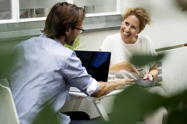 Happy couple working from home, sitting in their garden - HHLMF00564