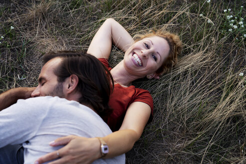 Happy couple cuddling, lying on a meadow - HHLMF00569