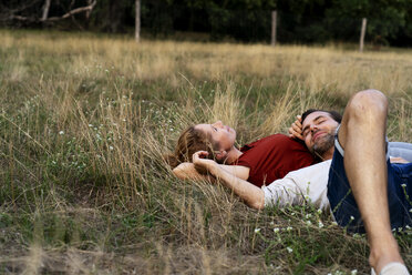 Happy couple cuddling, lying on a meadow - HHLMF00570