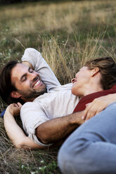 Happy couple cuddling, lying on a meadow - HHLMF00571