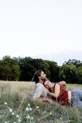 Happy couple cuddling, lying on a meadow - HHLMF00575