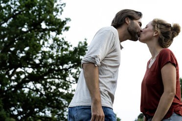 Happy couple in nature, standing face to face, kissing each other - HHLMF00591