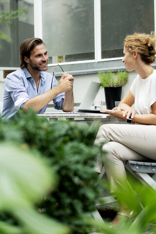 Glückliches Paar, das von zu Hause aus arbeitet und in seinem Garten sitzt, lizenzfreies Stockfoto