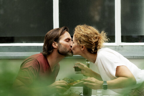 Glückliches Paar, das sich am Tisch küsst, Pizza isst und Wein trinkt - HHLMF00610