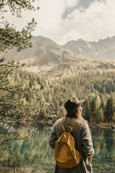 Switzerland, Engadin, woman on a hiking trip standing at lakeside in mountainscape - LHPF00133