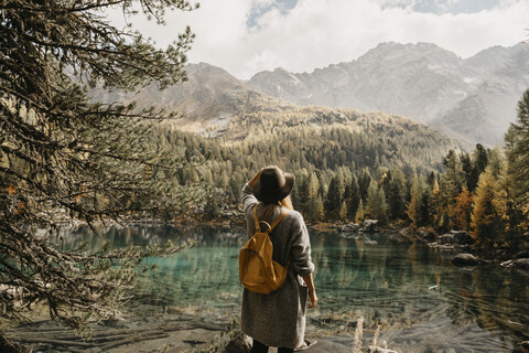 Schweiz, Engadin, Frau auf Wanderschaft am Seeufer stehend in Berglandschaft, lizenzfreies Stockfoto