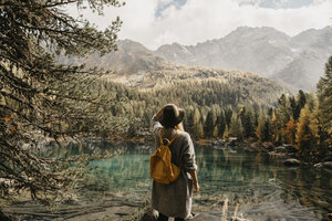 Schweiz, Engadin, Frau auf Wanderschaft am Seeufer stehend in Berglandschaft - LHPF00134