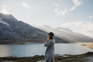 Schweiz, Engadin, Frau steht am Seeufer in Berglandschaft - LHPF00138
