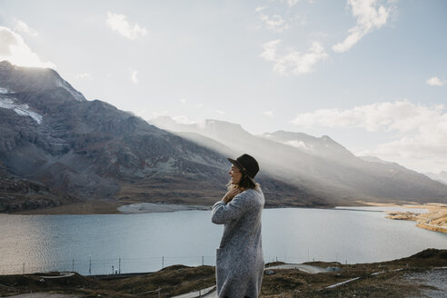 Switzerland, Engadin, woman standing at lakeside in mountainscape - LHPF00138