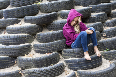 Trauriges Mädchen sitzt allein auf dem Spielplatz, lizenzfreies Stockfoto