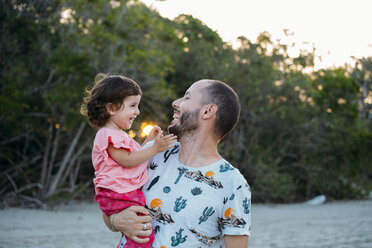 Australia, Queensland, Mackay, Cape Hillsborough National Park, happy father holding his daughter at the beach at sunset - GEMF02572