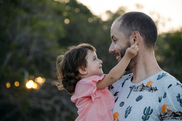 Happy father holding his daughter outdoors at sunset - GEMF02574