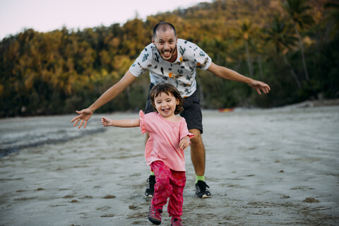 Australien, Queensland, Mackay, Cape Hillsborough National Park, glücklicher Vater läuft seiner Tochter am Strand hinterher, lizenzfreies Stockfoto