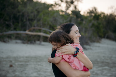 Australia, Queensland, Mackay, Cape Hillsborough National Park, happy mother hugging her daughter at the beach - GEMF02578