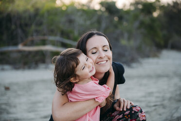Australia, Queensland, Mackay, Cape Hillsborough National Park, happy mother hugging her daughter at the beach - GEMF02581