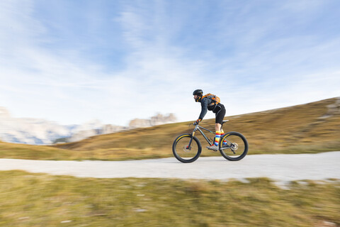 Italien, Cortina d'Ampezzo, Kameraschwenk über einen Mann mit Mountainbike in den Dolomiten, lizenzfreies Stockfoto