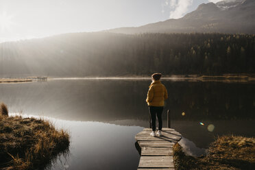 Schweiz, Engadin, Stazersee, Frau steht auf einem Steg am Seeufer in der Morgensonne - LHPF00142