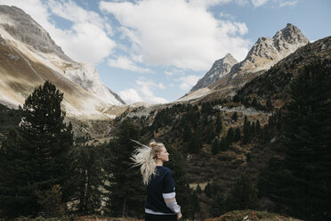 Schweiz, Graubünden, Albulapass, junge Frau mit windzerzaustem Haar in Berglandschaft stehend - LHPF00152