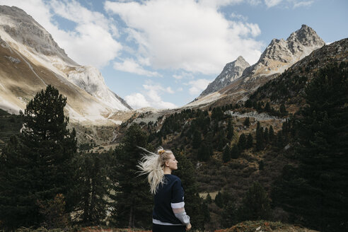 Switzerland, Grisons, Albula Pass, young woman with windswept hair standing in mountainscape - LHPF00152