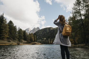 Switzerland, Grisons, Albula Pass, woman on a hiking trip standing at lakeside in mountainscape - LHPF00154