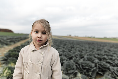 Porträt eines Mädchens, das auf einem Kohlfeld steht, lizenzfreies Stockfoto