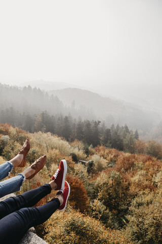 Germany, Black Forest, Sitzenkirch, legs of two women sitting at Sausenburg Castle above mountain forest stock photo