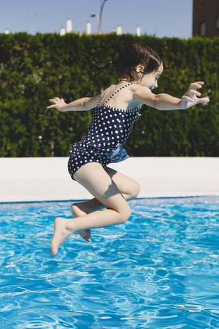 Glückliches kleines Mädchen springt ins Schwimmbad, lizenzfreies Stockfoto