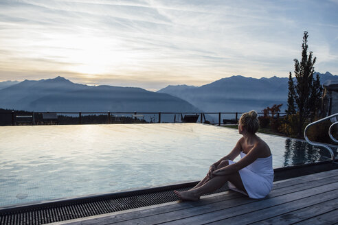 Frau entspannt sich am Pool, eingewickelt in ein Handtuch - LHPF00176