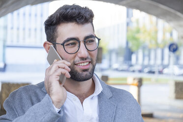 Porträt eines lächelnden jungen Geschäftsmannes am Telefon - TCF05983