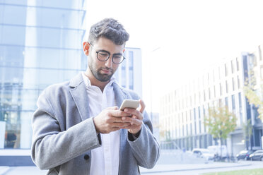 Porträt eines jungen Geschäftsmannes, der ein Mobiltelefon benutzt - TCF05984