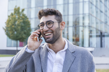 Porträt eines lachenden jungen Geschäftsmannes am Telefon - TCF05985