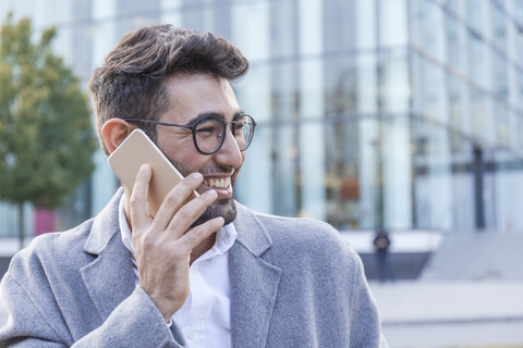 Porträt eines lachenden jungen Geschäftsmannes am Telefon, lizenzfreies Stockfoto