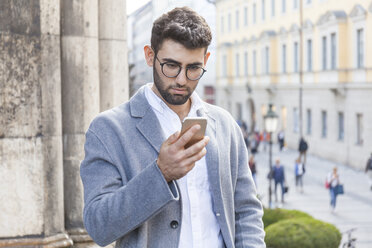 Germany, Munich, portrait of young businessman using cell phone in the city - TCF05987