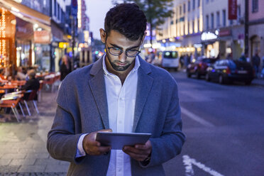 Deutschland, München, junger Geschäftsmann mit digitalem Tablet in der Stadt in der Abenddämmerung - TCF05999