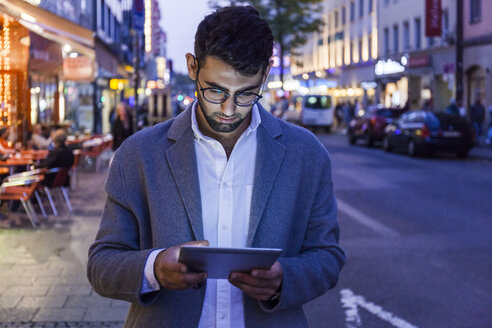 Deutschland, München, junger Geschäftsmann mit digitalem Tablet in der Stadt in der Abenddämmerung - TCF05999