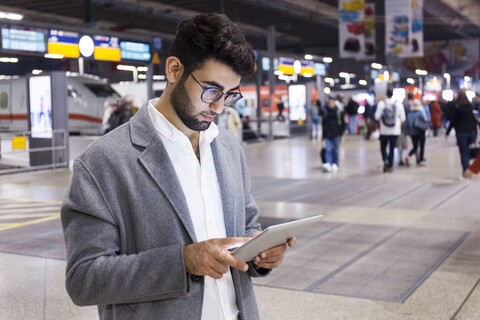 Germany, Munich, young businessman using digital tablet at central station stock photo