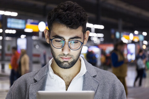 Deutschland, München, Porträt eines jungen Geschäftsmannes mit digitalem Tablet am Hauptbahnhof, lizenzfreies Stockfoto
