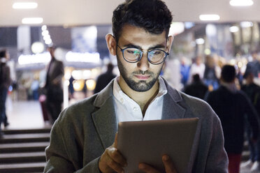 Germany, Munich, portrait of young businessman using digital tablet at central station - TCF06004